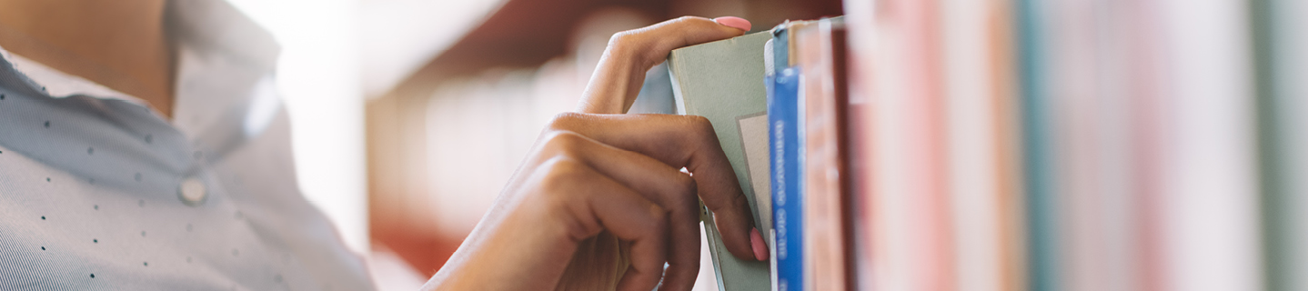 Hand taking a book off a shelf